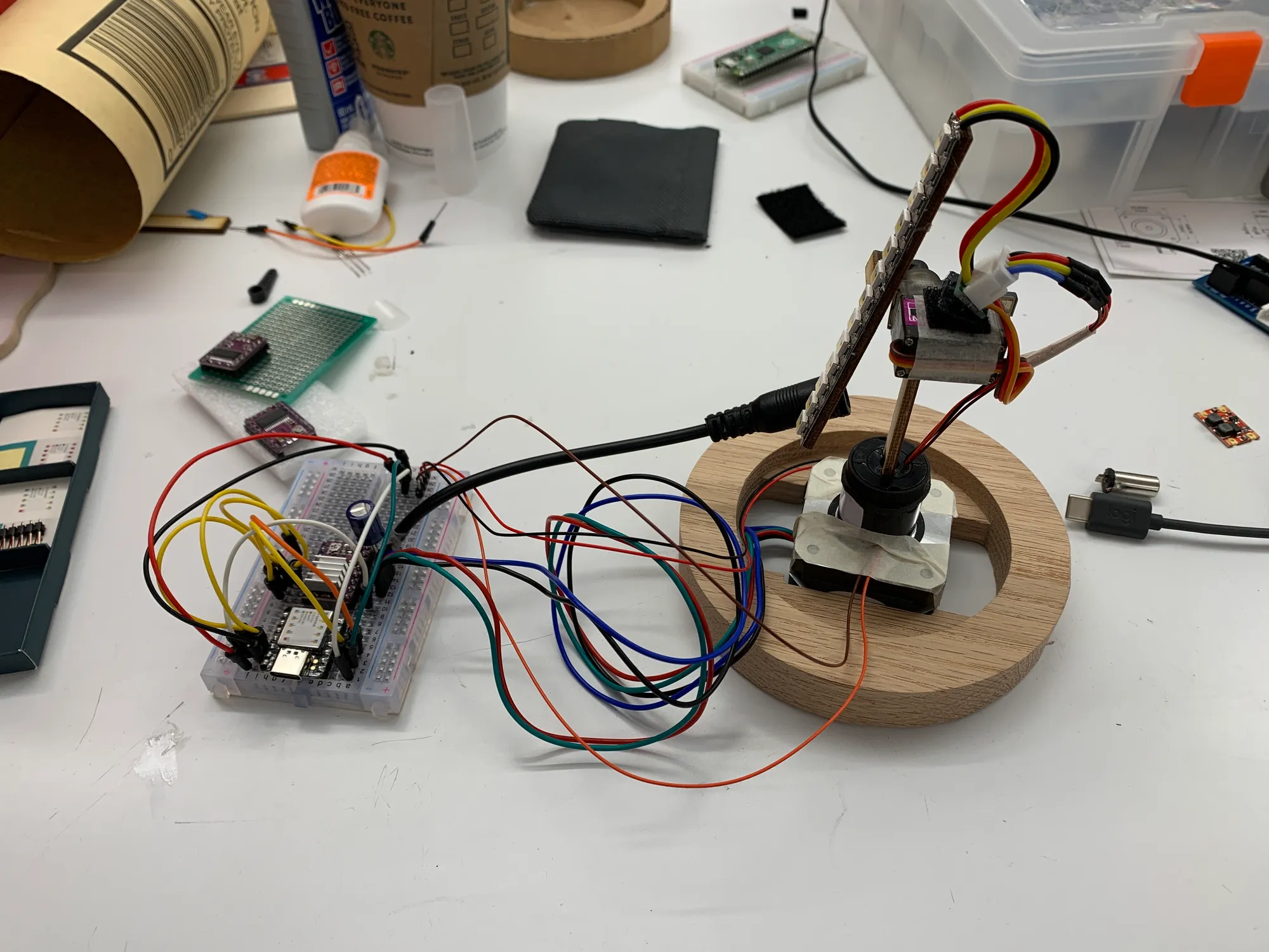 prototyped circuit on a breadboad next to the wood base with motor and leds linked by wires