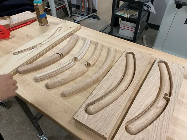 Wooden hanger arms and their CNC-cut molds arranged on a workbench