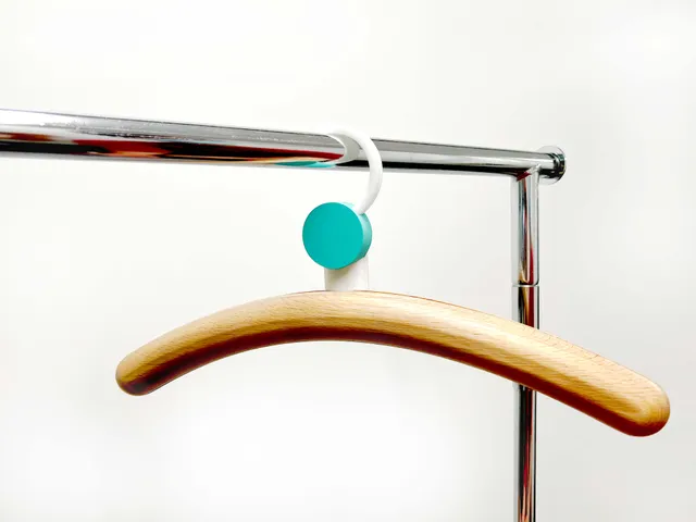 Wooden hanger with a white rotating hook and turquoise pivot hanging from a chrome rail