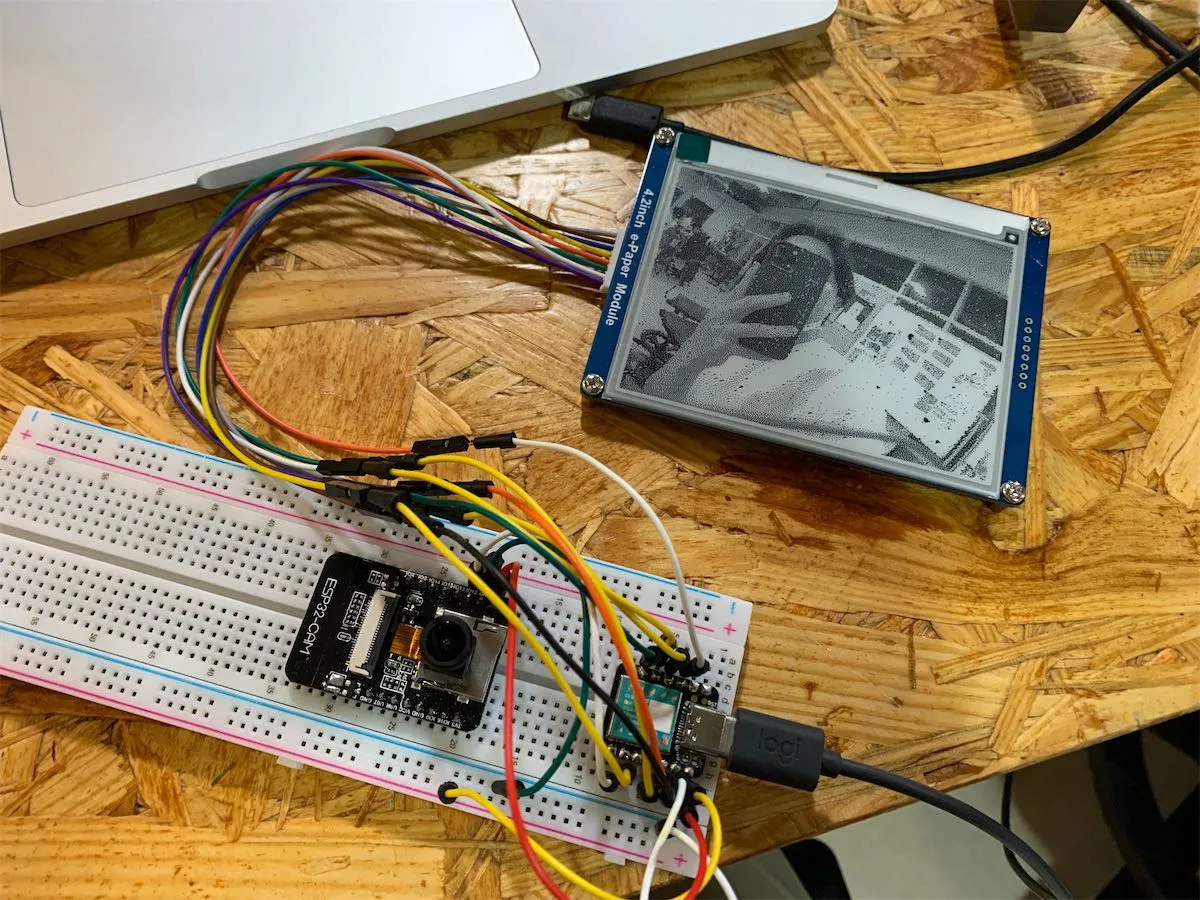 camera module on a breadboard connected to a e-paper display showing a picture the camera just take.